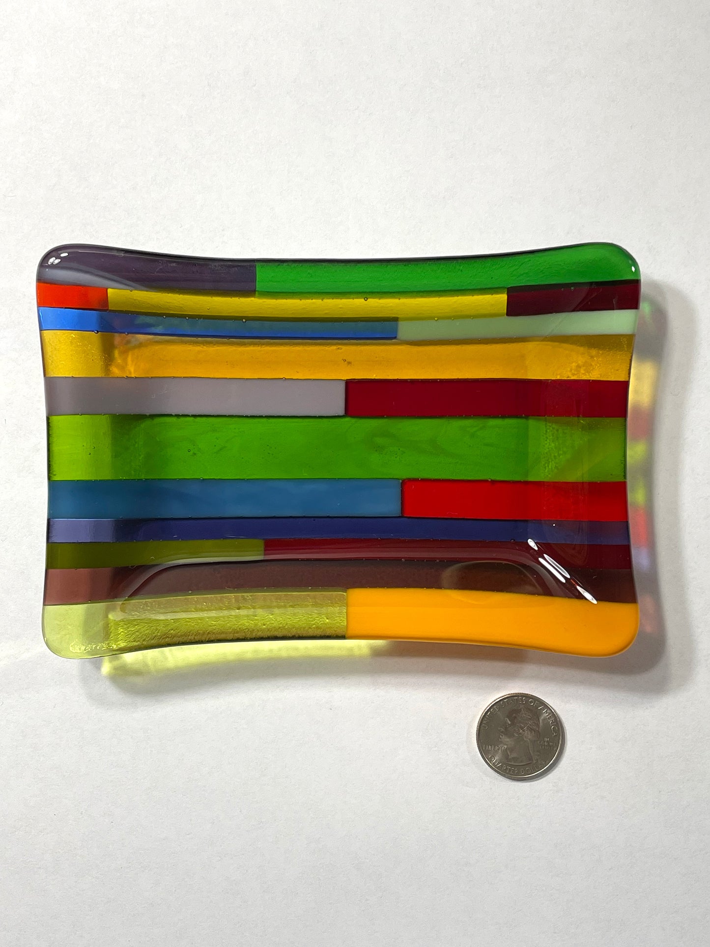 Green dominant multicolor hard-edge fused glass dish by AWinburnART with quarter to show size