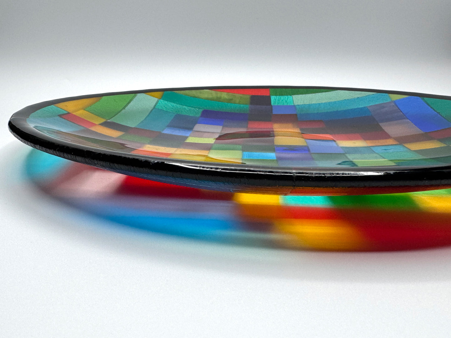 Side view of Rhythm fused glass art platter by AWinburnART showing depth, luminous multicolor glass edge, and kiln-fired construction detail