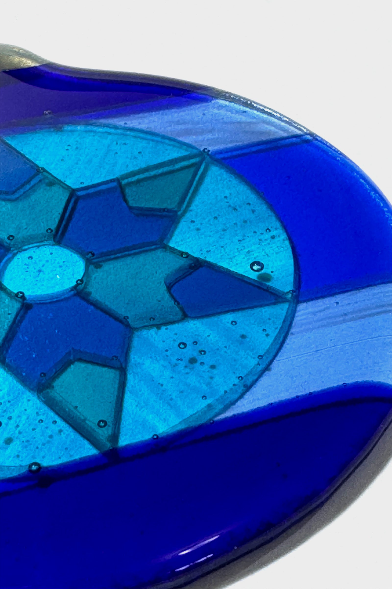 Close-up detail of Blue 6-Point Star Fused Glass Ornament showing hand cut blue glass pieces  in varying shades and opacities with kiln-fired texture.