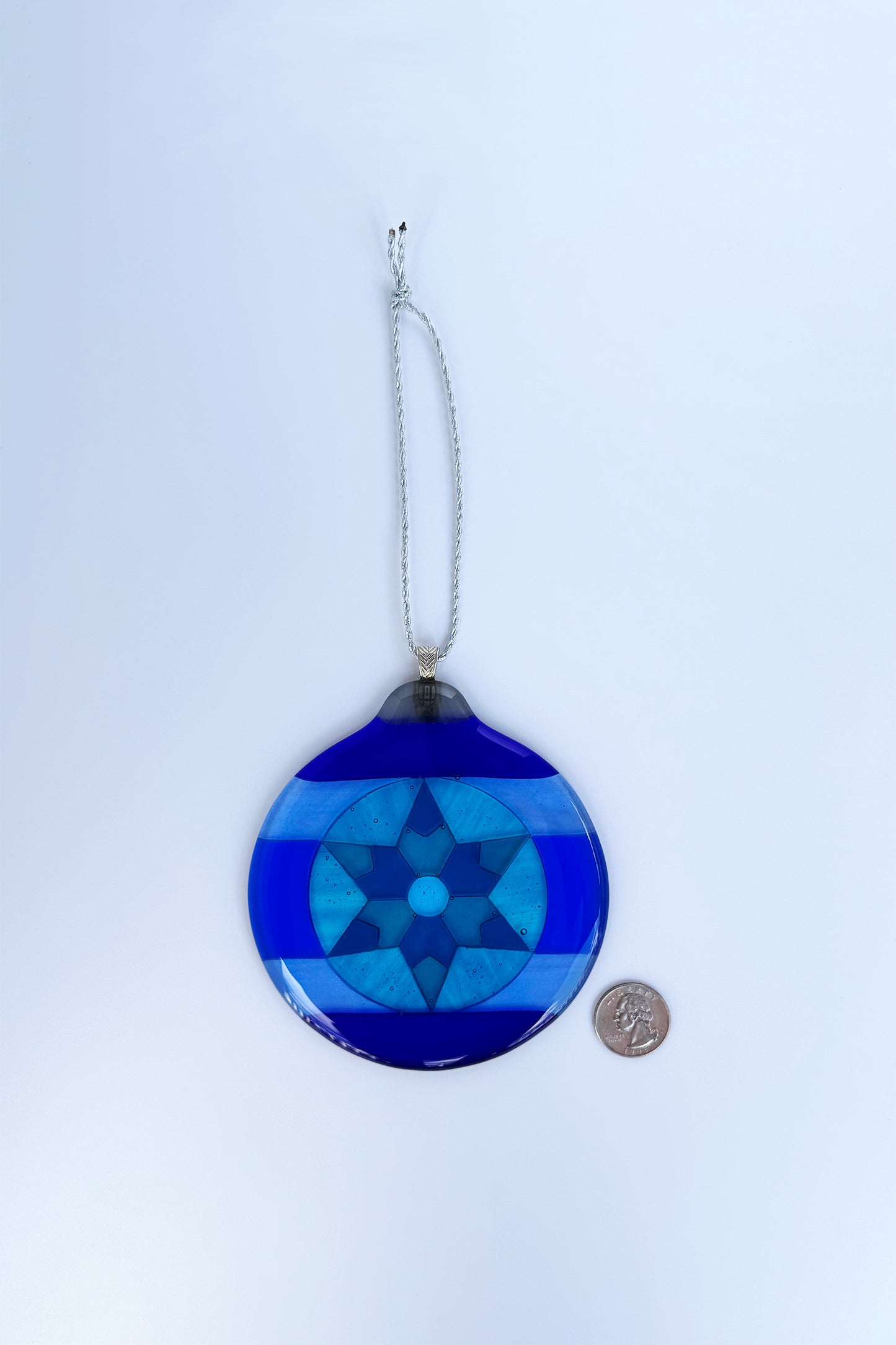 Blue 6-Point Star Fused Glass Ornament by AWinburnART shown next to a quarter for scale, approximately 4.5 inches wide.