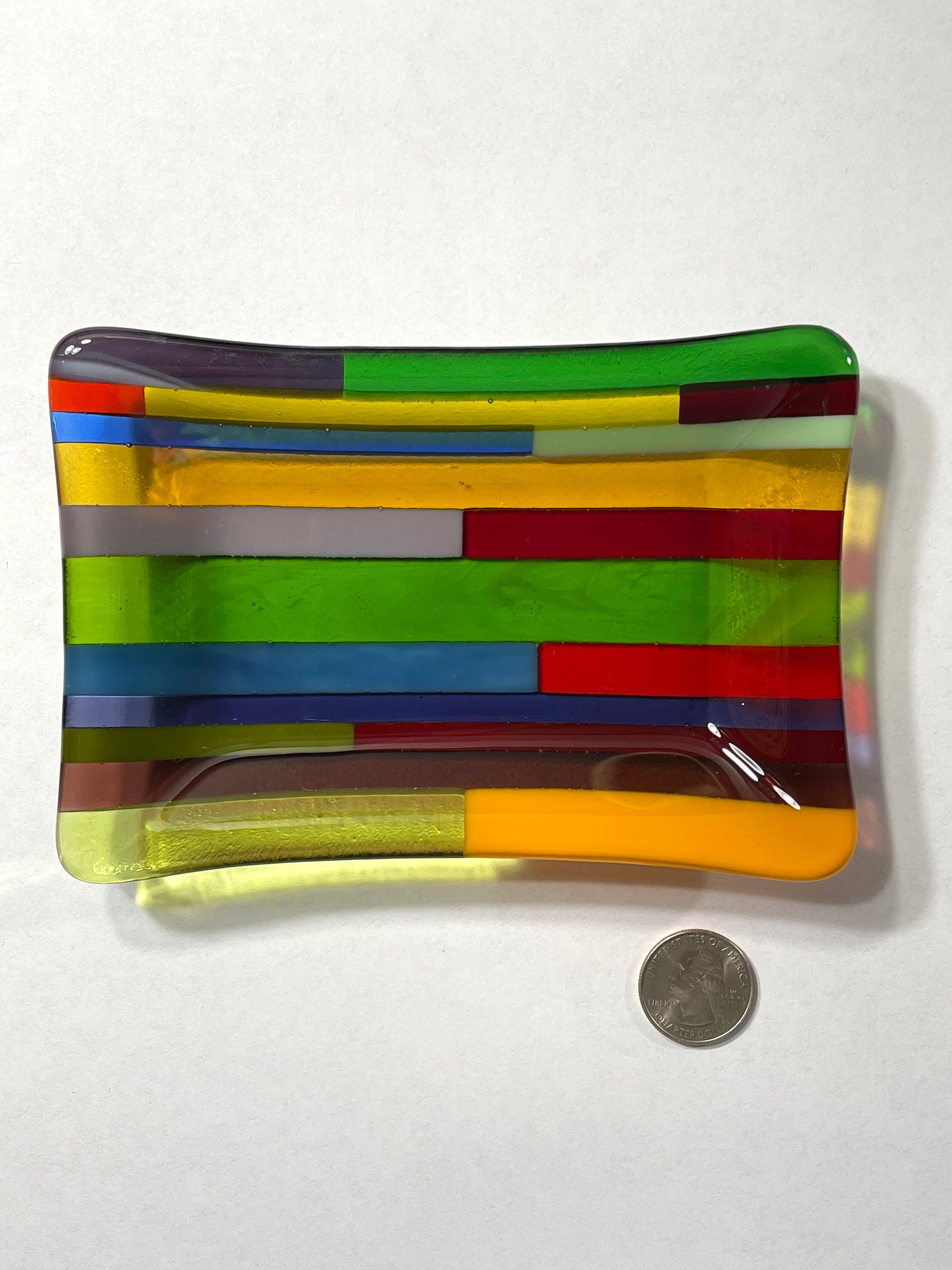 Green dominant multicolor hard-edge fused glass dish by AWinburnART with quarter to show size
