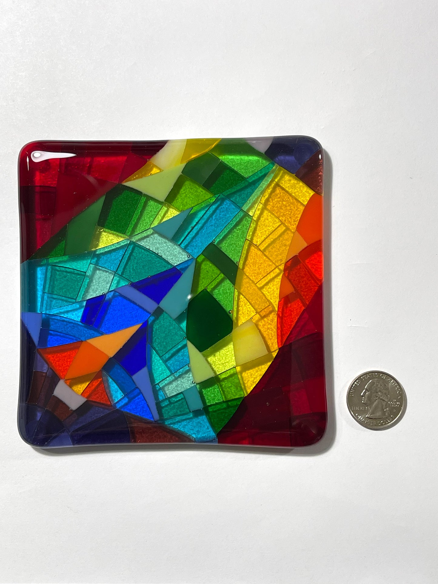 Lofty Dream, a handcrafted fused glass art coaster shown with a quarter for scale, 5x5 inches, multicolor hard-edge design by Angie of AWinburnART.