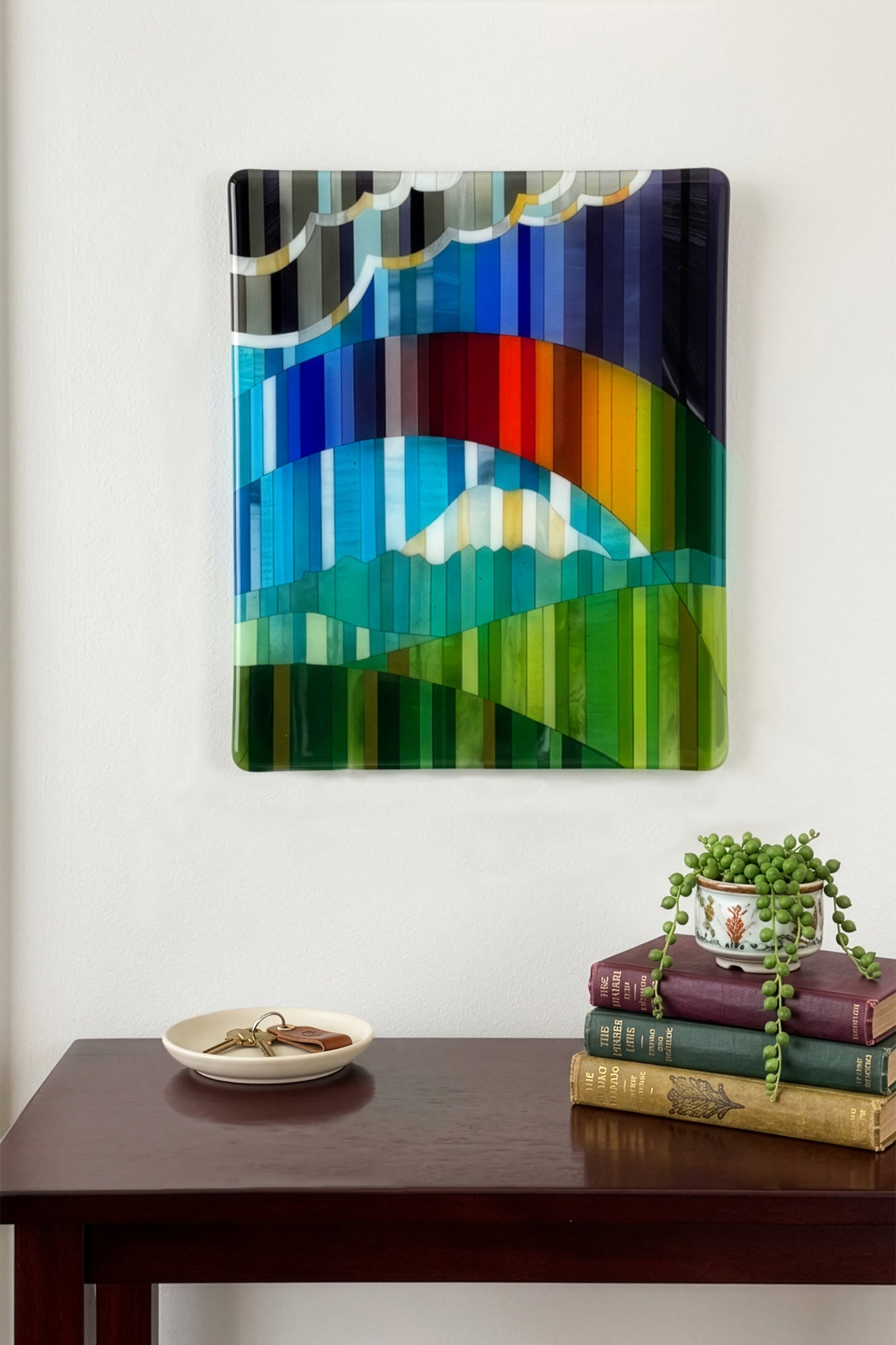 Promise fused glass wall art by AWinburnART displayed above a wooden entry table, shown in natural environment.