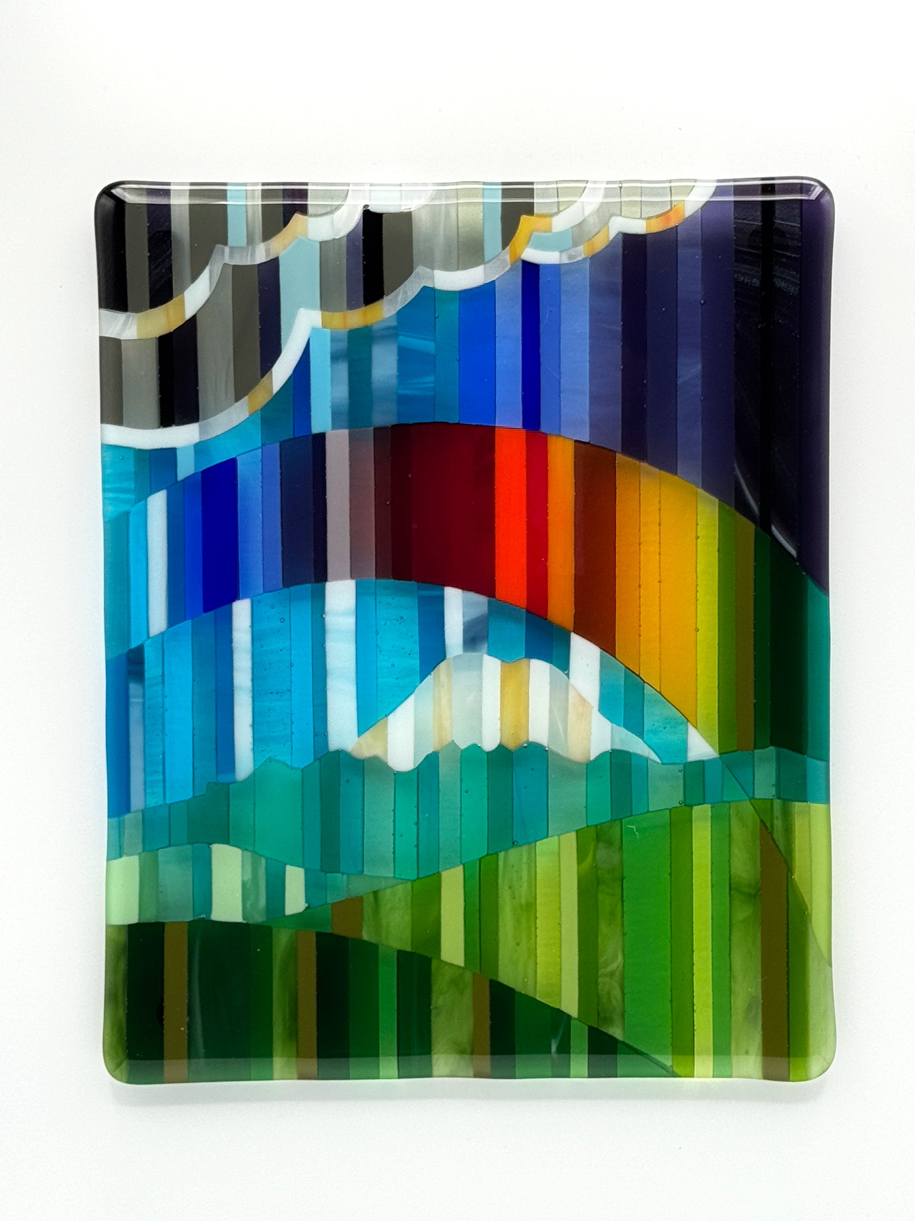 Promise is original fused glass wall art by AWinburnART, depicting storm clouds, a rainbow arc, rolling mountain, and green hills rendered in vertical stripe composition with 236 hand-cut multicolor glass pieces"