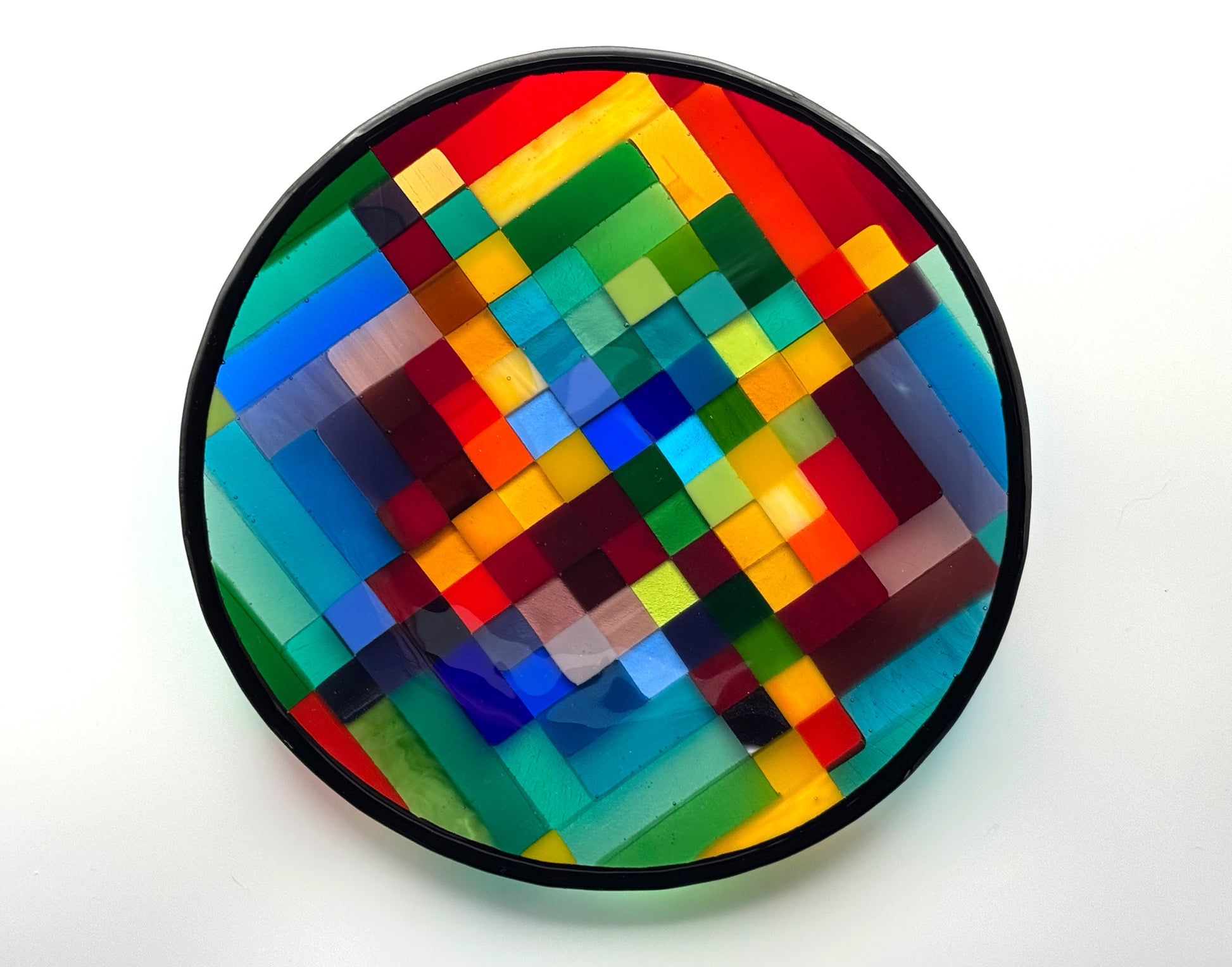 Rhythm is an original fused glass art platter by AWinburnART, circular form with bold multicolor pixel-quilt pattern of hand-cut glass squares in red, blue, green, yellow, teal, and orange with black rim